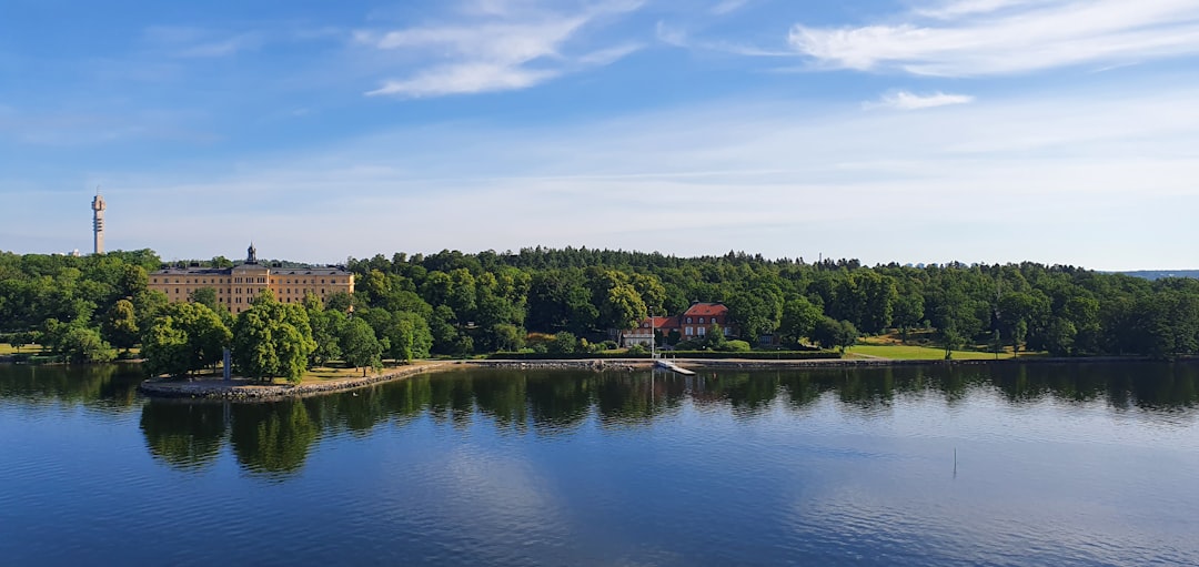 a lake surrounded by trees and a large building